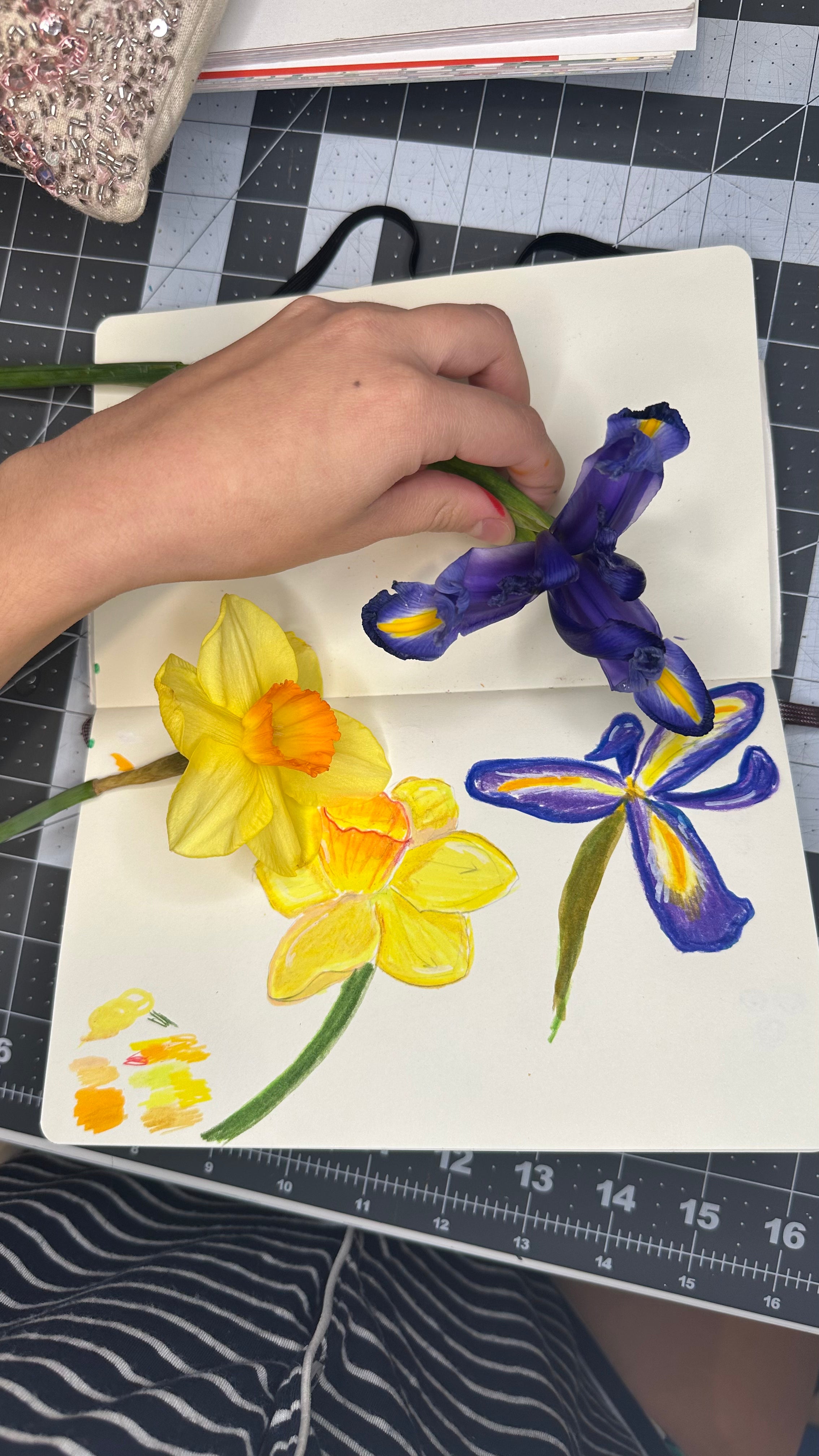 Hand holding a painting of flowers on a grid background